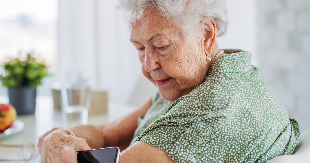 A senior woman uses her smartphone to check her glucose monitor, a tool that can be extremely helpful for diabetes care.