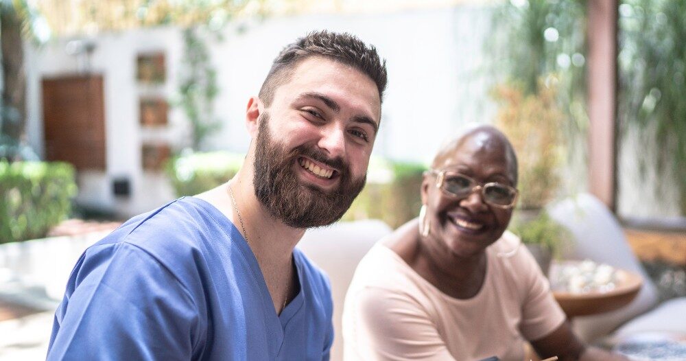 A man enjoys his caregiver job as he works with a client.