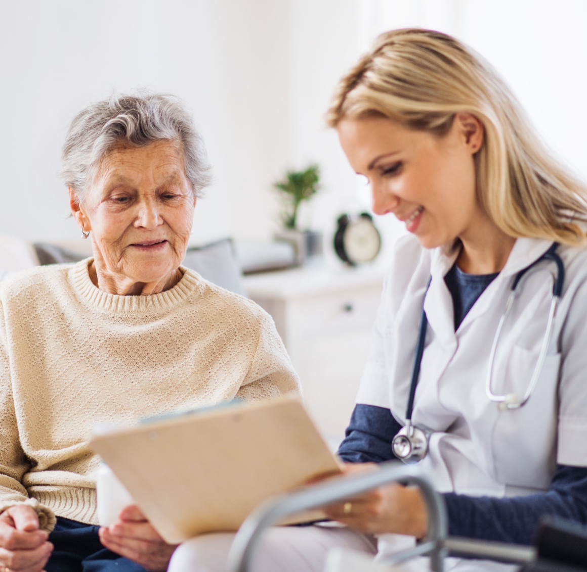 A caregiver shows documents to an older patient, representing what a home nurse may do.