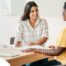 A woman happily interviews another woman, representing how well caregiver interviews can go when prepared.