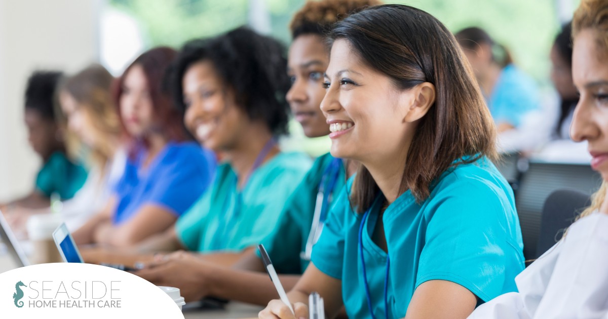 Several students in scrubs happily attend a class, representing caregiver training.