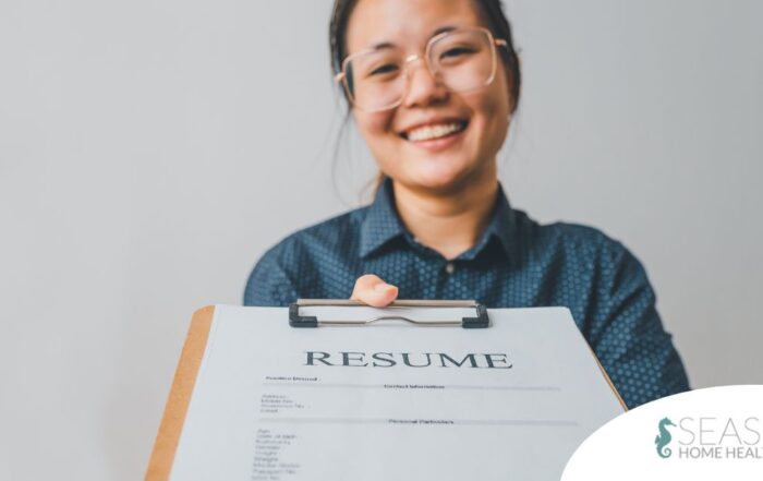 A woman happily hands in a resume, representing a successfully written caregiver resume.